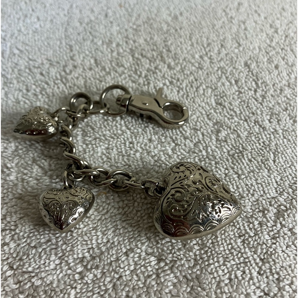 Kathy VanZeeland three silver puff heart purse accessorie. Secure closure.